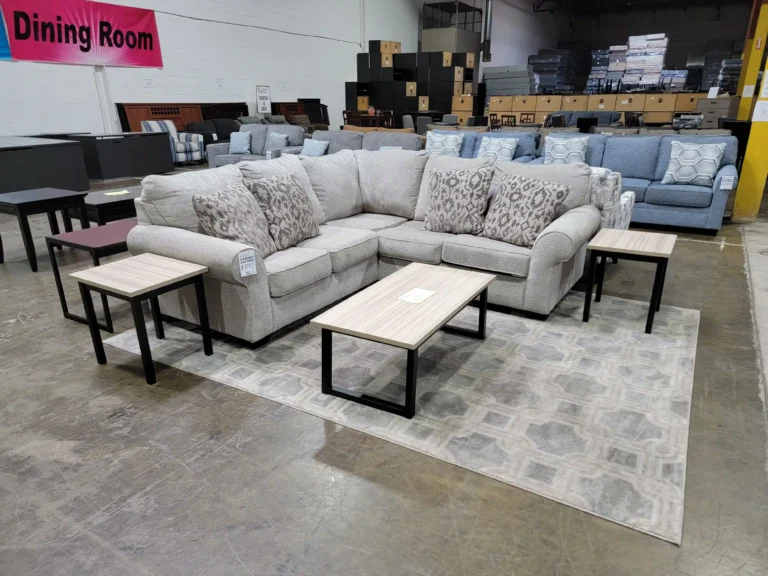 “Furniture clearance display with off-white sectional, coffee table, multiple sofas, loveseats, chairs, and TV stand.”