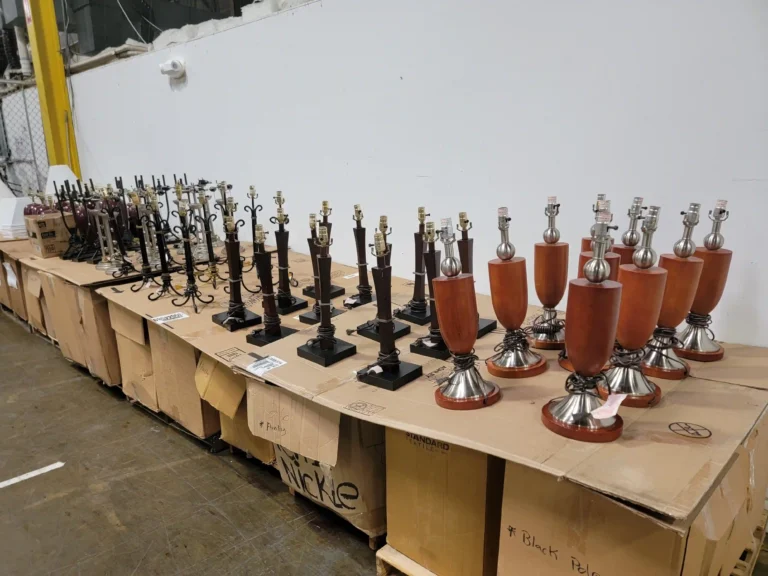 “Table lamps of various colors and shapes displayed on boxes, with additional lamps visible in the back.”